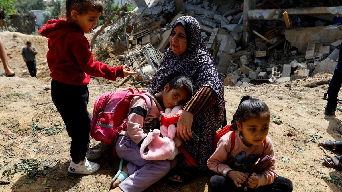 فلسطينية تدعى فاطمة بشير مع حفيداتها يجلسن بجانب ركام منزلهم.  - رويترز