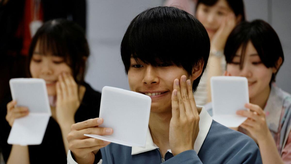 يتعلم الطلاب كيفية ممارسة عضلات الوجه بالمرايا في دورة تدريبية على الابتسامة في مدرسة Sokei للفنون في طوكيو ، اليابان ، 30 مايو 2023. - ملف رويترز