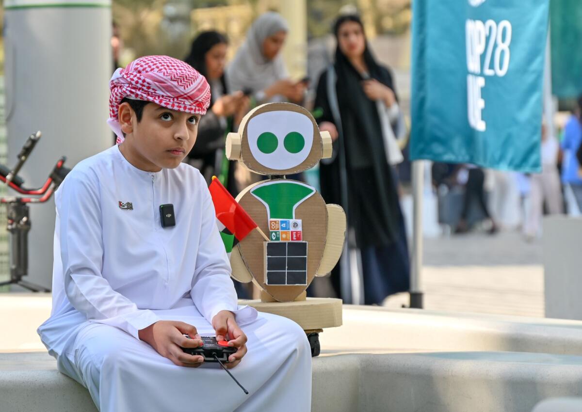 الصبي الإماراتي مسعد سالم الخزيمي، البالغ من العمر عشر سنوات، مع روبوته MR COP في مؤتمر COP28 في الإمارات العربية المتحدة، الذي أقيم في مدينة إكسبو بدبي في 8 ديسمبر 2023. (الصورة: م. سجاد / خليج تايمز)