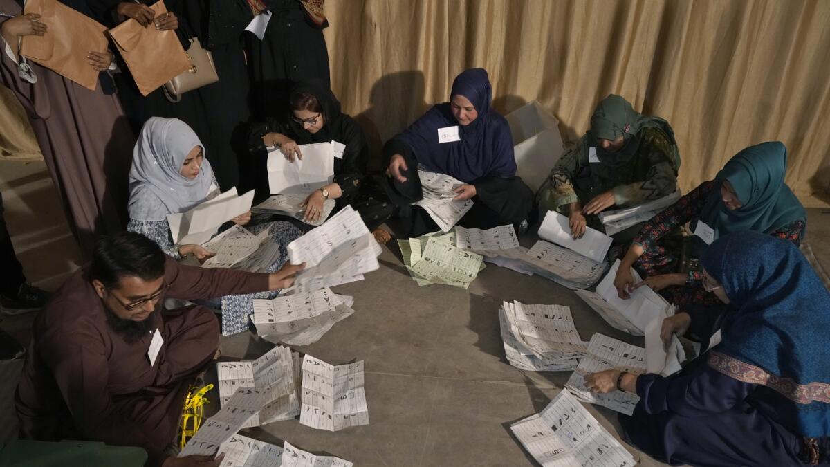 أعضاء طاقم الاقتراع يقومون بفرز الأصوات في كراتشي.  — ا ف ب
