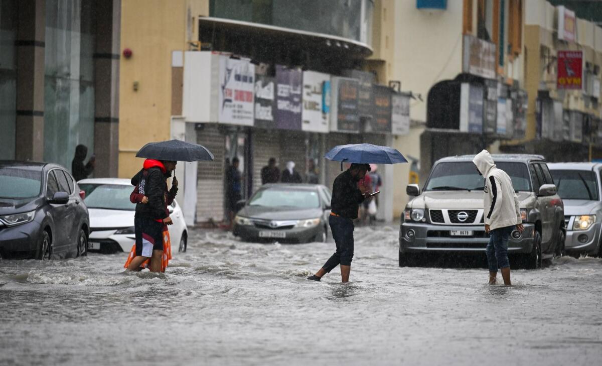 سكان يتنقلون عبر طريق غمرته المياه في الشارقة بسبب هطول أمطار غزيرة على الإمارات صباح يوم الاثنين.  صورة KT: محمد سجاد