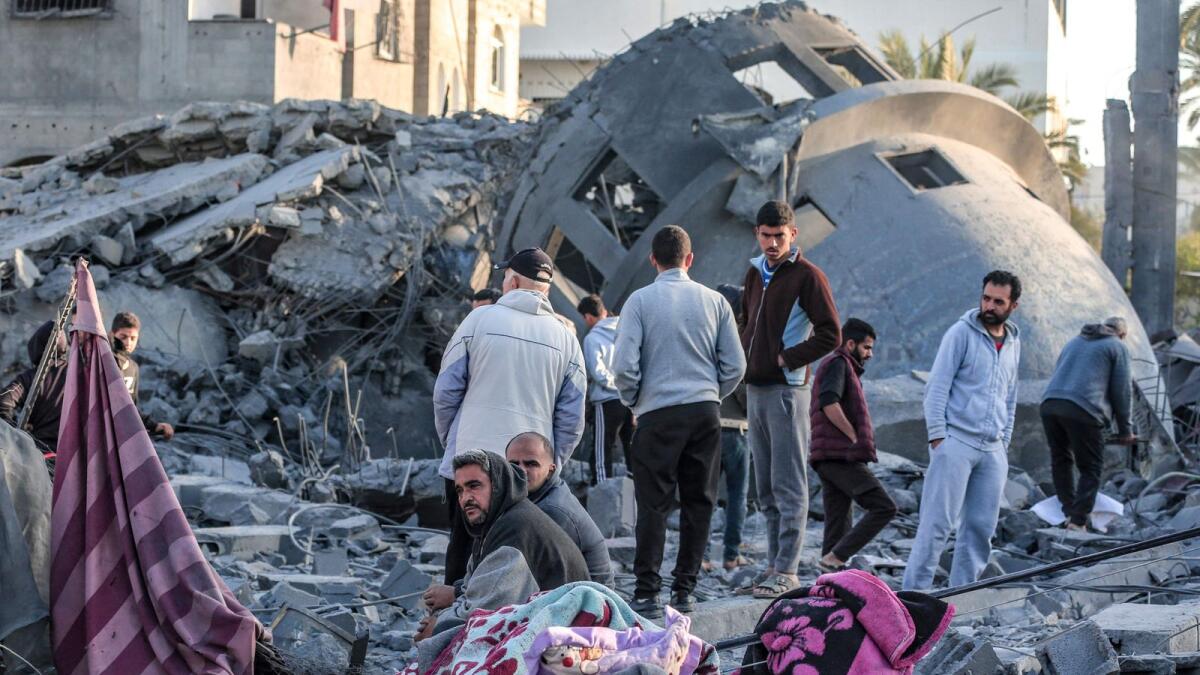 فلسطينيون يقفون وسط أنقاض المسجد الذي دمرته غارات إسرائيلية في دير البلح وسط قطاع غزة.  – وكالة فرانس برس