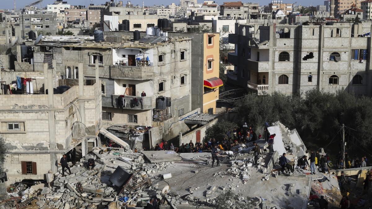 فلسطينيون ينظرون إلى الدمار الذي خلفته غارة إسرائيلية على مبنى سكني في رفح.  — ا ف ب