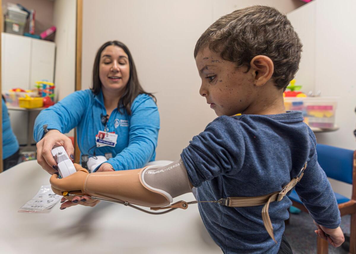يتعلم عمر أبو كويك البالغ من العمر أربع سنوات استخدام ذراعه الاصطناعية الجديدة مع المعالج المهني ميغان جوسنبرجر في مستشفى شرينرز للأطفال في 28 فبراير 2024 في فيلادلفيا.  — ا ف ب