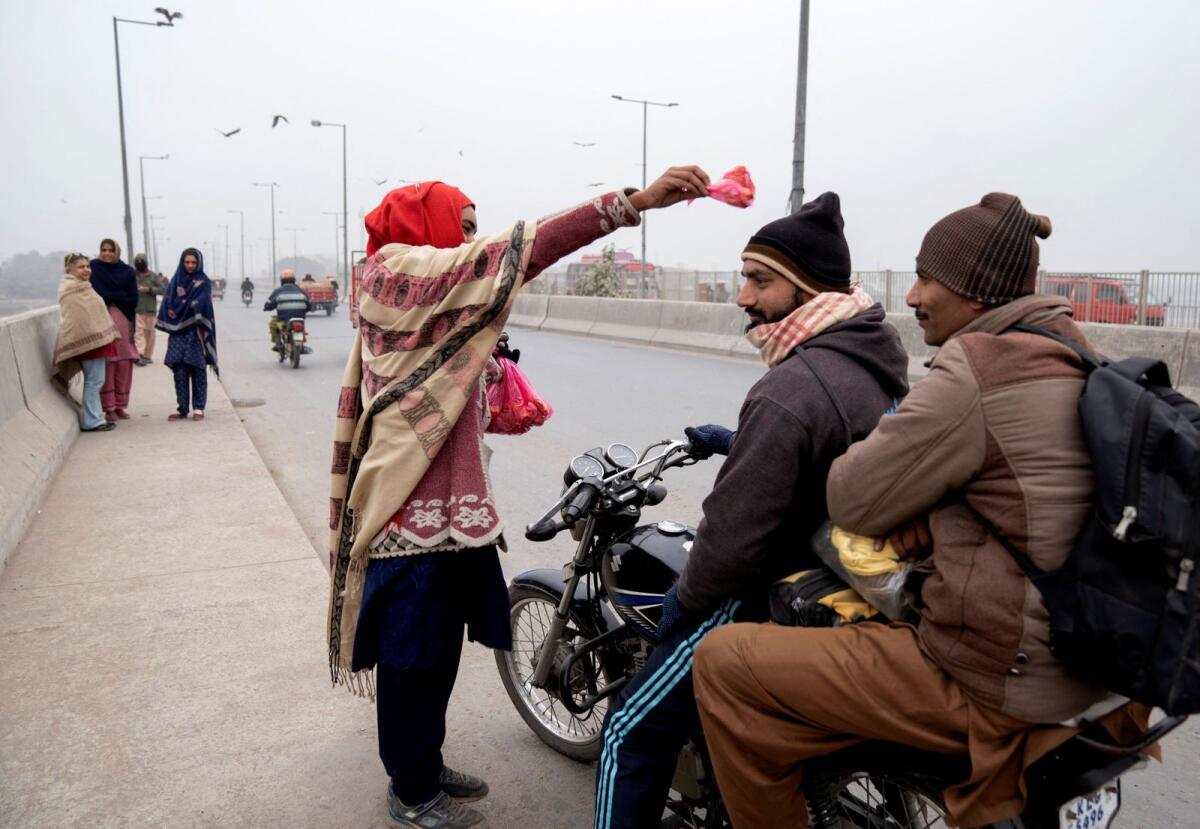 امرأة تبارك أحد العملاء باللحم لإطعام الطيور في لاهور.  – رويترز