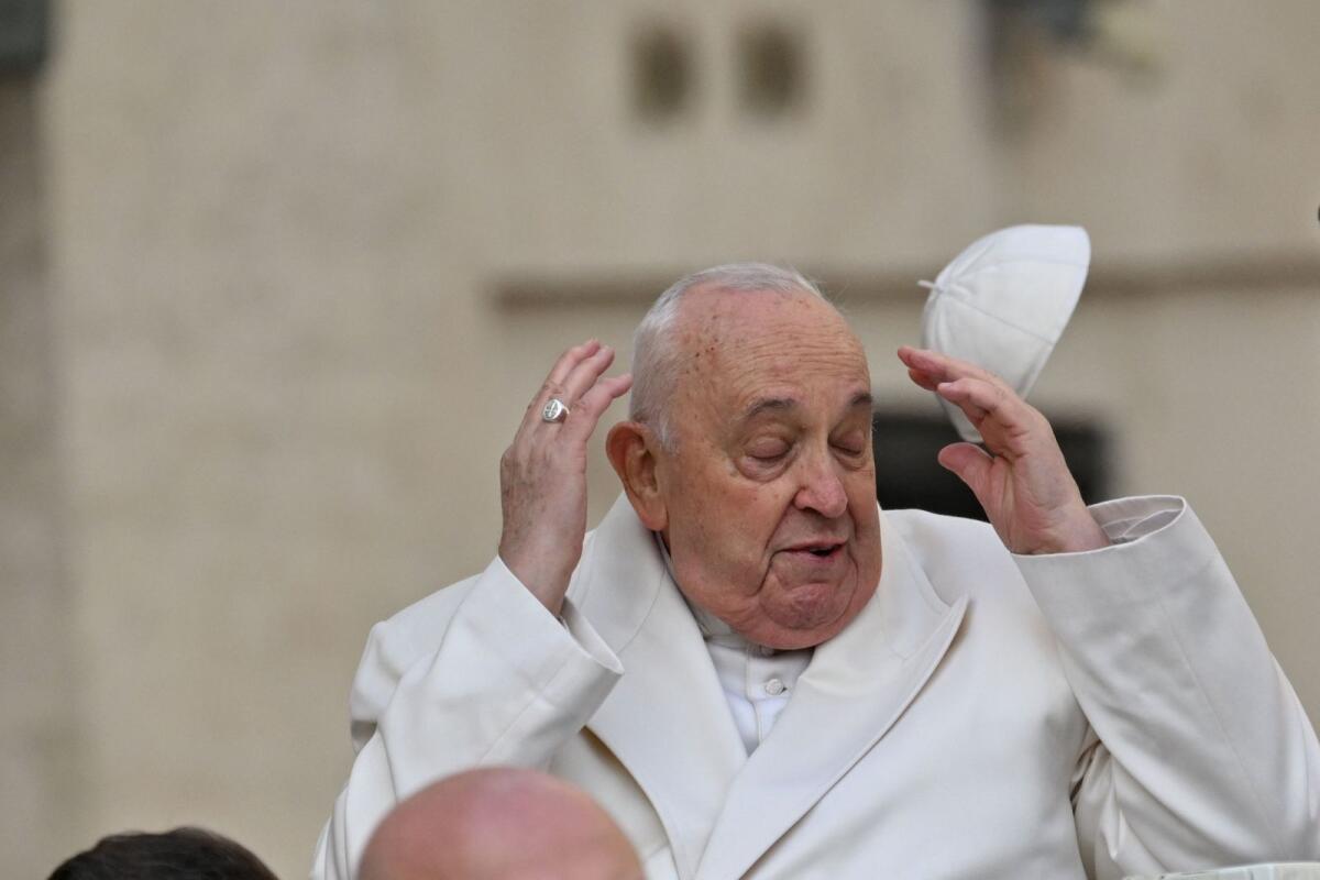تطايرت الرياح قبعة البابا فرانسيس عن رأسه أثناء وصوله لجمهوره العام في ساحة القديس بطرس في الفاتيكان في 13 مارس 2024. – AFP