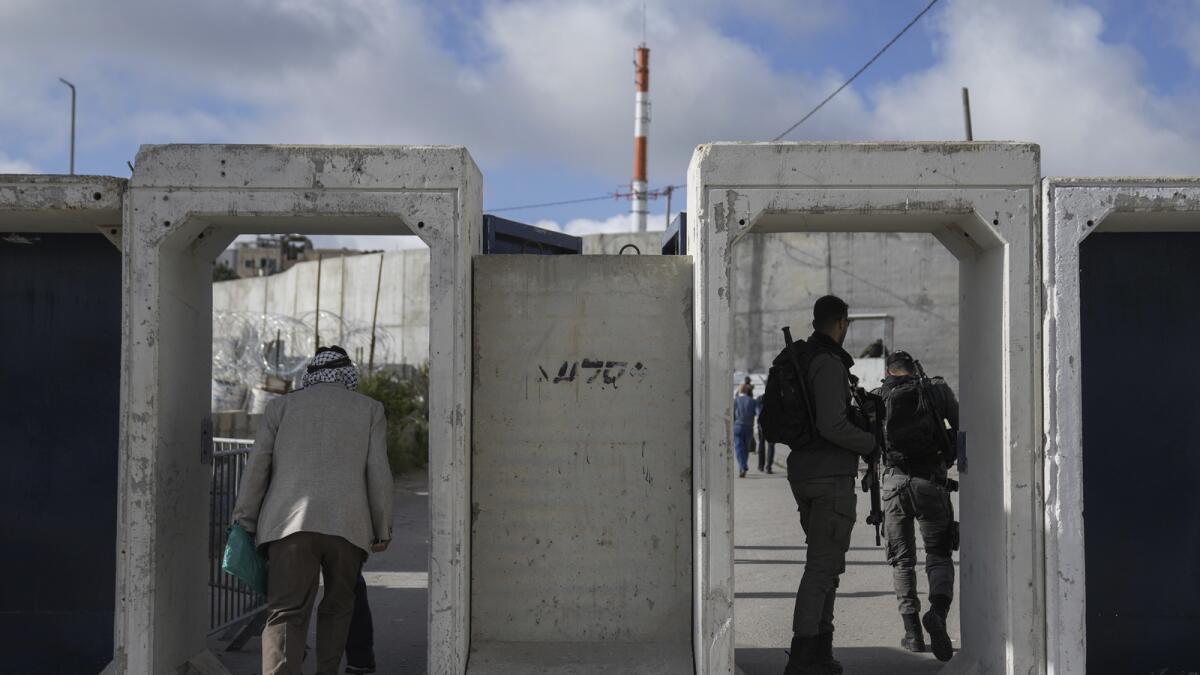 فلسطينيون يعبرون من حاجز قلنديا العسكري الإسرائيلي بالقرب من مدينة رام الله بالضفة الغربية إلى القدس.  — ا ف ب