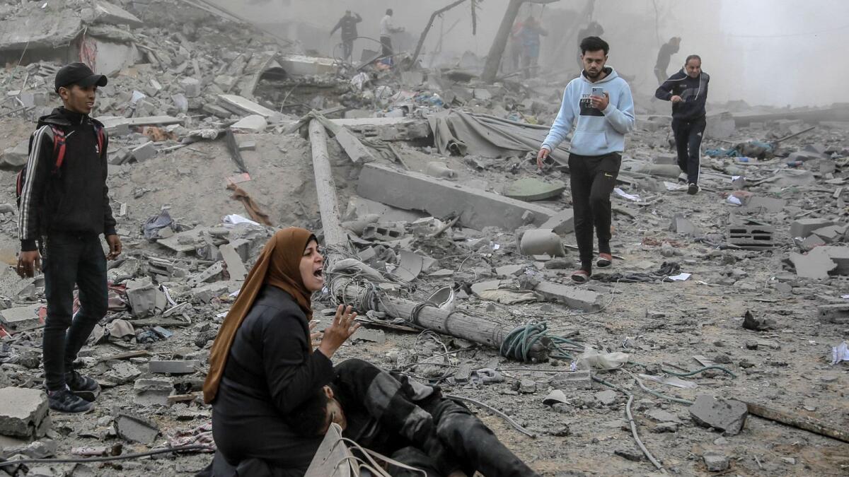 رد فعل امرأة فلسطينية وهي تحتضن طفلاً جريحًا بعد القصف الإسرائيلي على وسط مدينة غزة.  – وكالة فرانس برس
