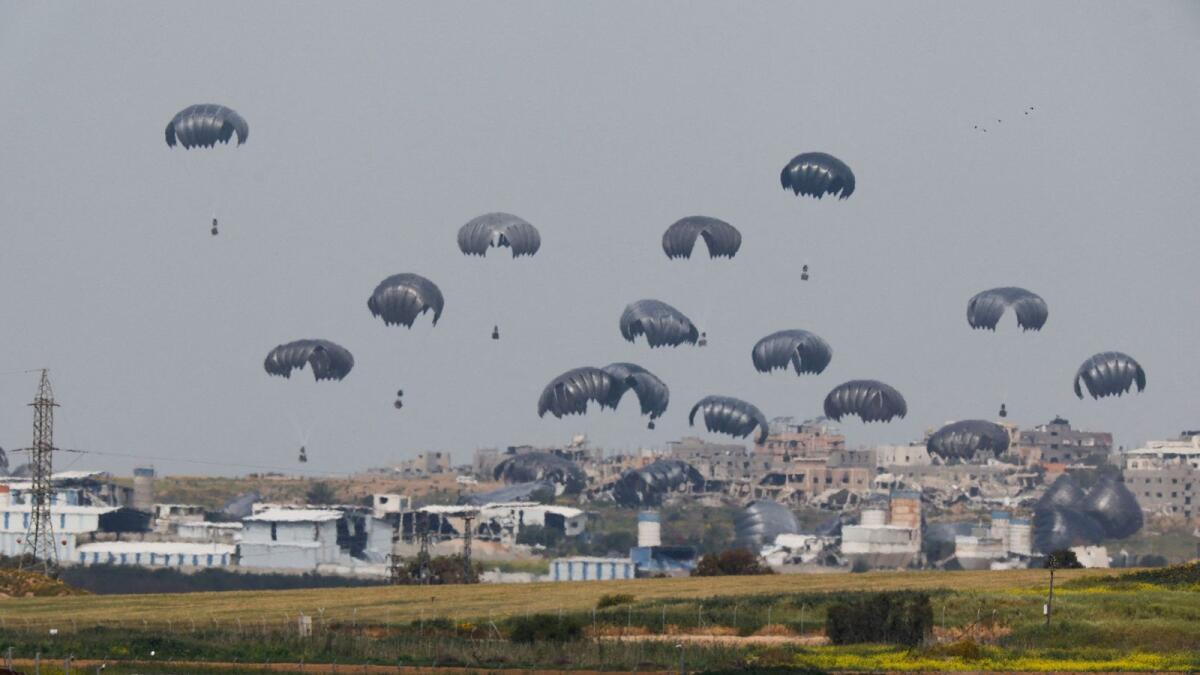 المساعدات الإنسانية تتساقط في السماء باتجاه قطاع غزة بعد إسقاطها من طائرة كما تظهر من حدود إسرائيل مع غزة.  – رويترز