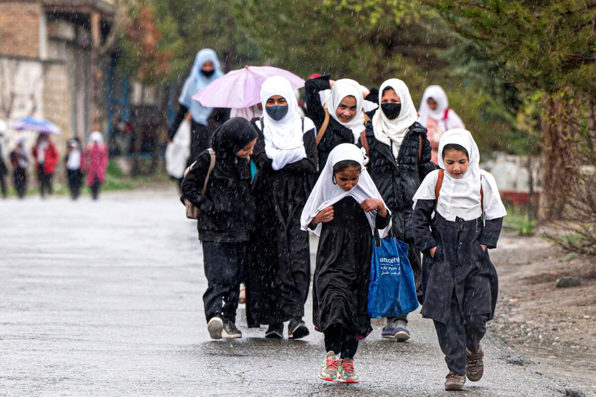 تلميذات أفغانيات يسيرن وسط هطول الأمطار على طول طريق في منطقة باغمان على مشارف كابول في 30 مارس 2023. – وكالة فرانس برس