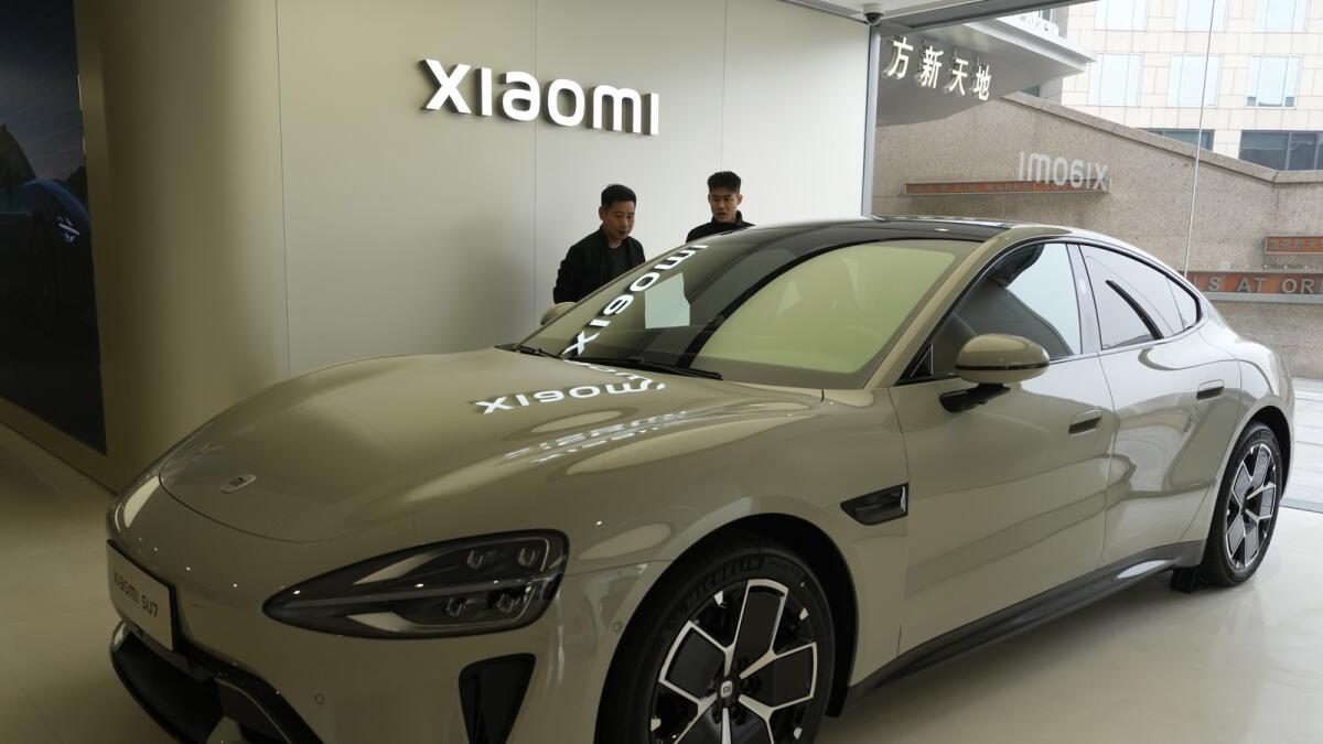 زوار المتجر الرئيسي لشركة Xiaomi Automobile ينظرون إلى السيارة الكهربائية Xiaomi SU7.  — ا ف ب