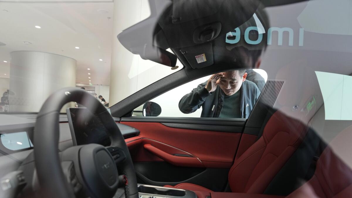 رجل يلقي نظرة خاطفة على الجزء الداخلي للسيارة الكهربائية Xiaomi SU7 المعروضة في بكين.  — ا ف ب