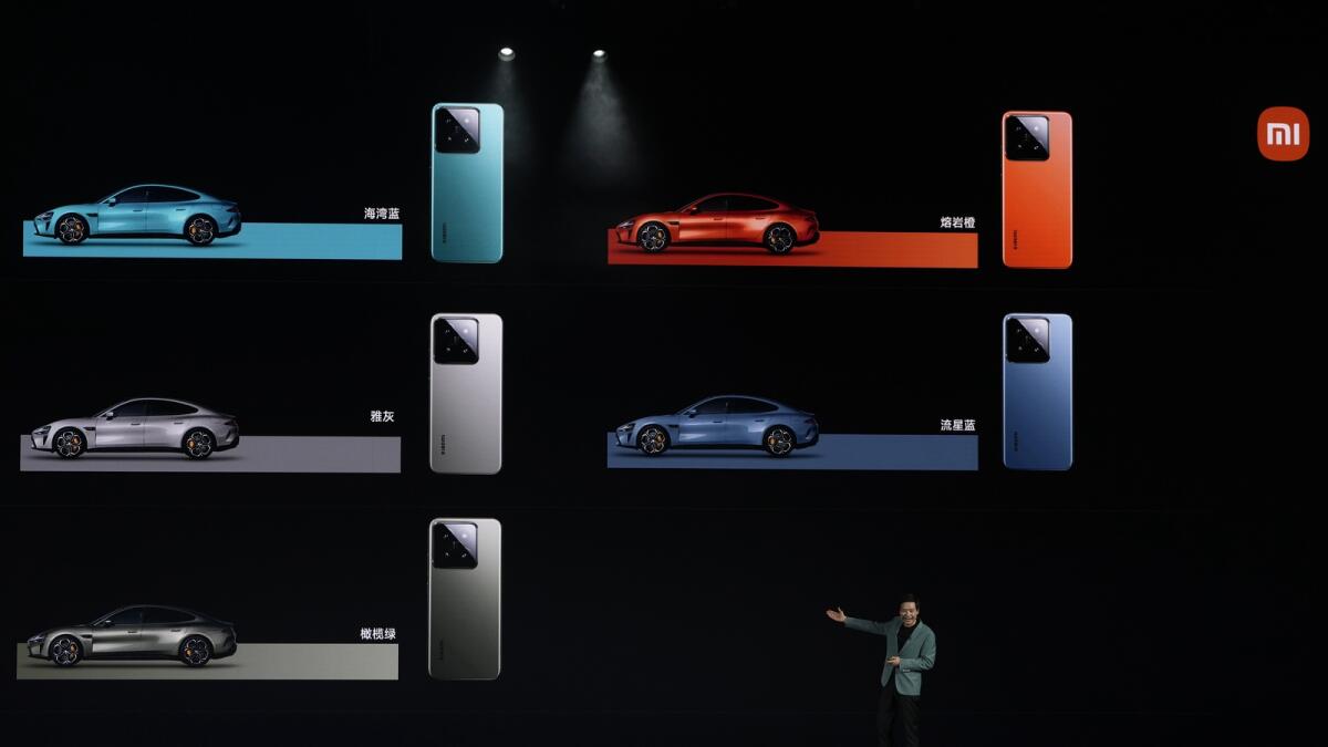 يعرض مؤسس شركة Xiaomi، Lei Jun، ألوان سيارة SU7، وهي سيارة سيدان رياضية بأربعة أبواب، مع هواتف Xiaomi الذكية المطابقة.  — ا ف ب