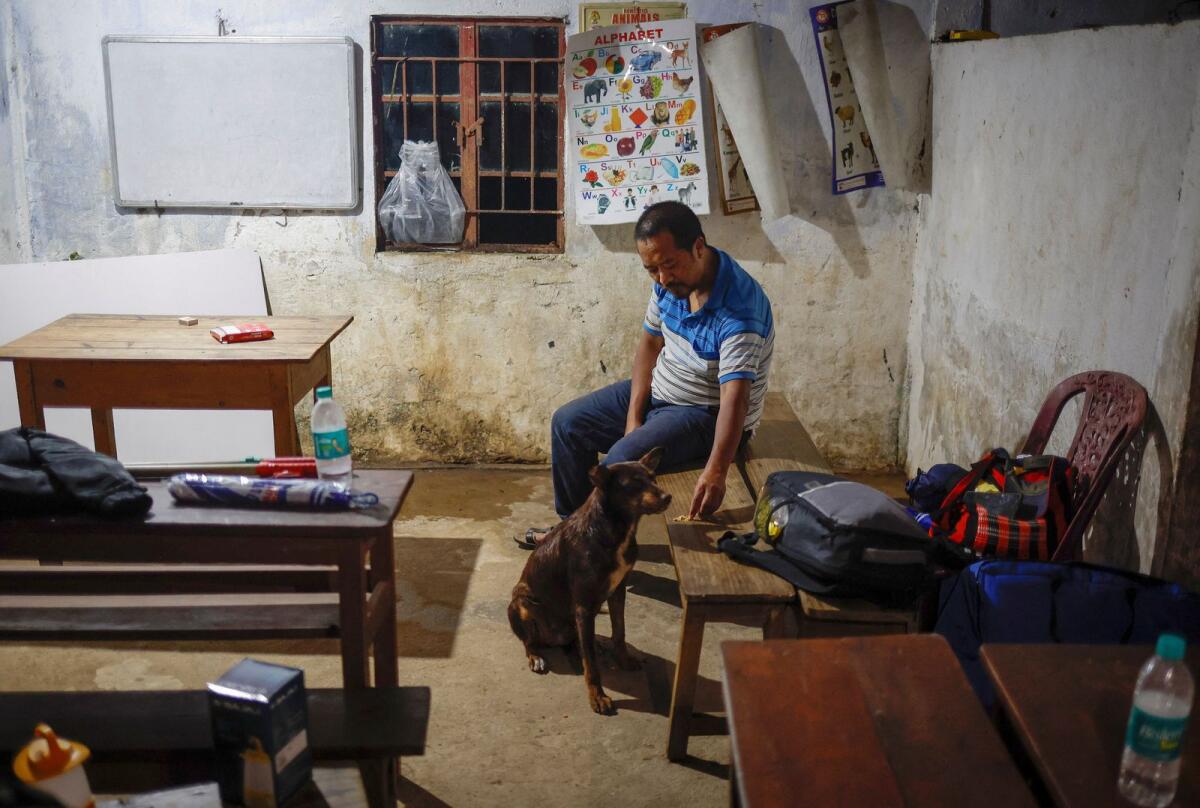 موظف الاقتراع دبليو. مونينغ بيلجيت مونسانغ يطعم كلبًا داخل مركز اقتراع بعد وصوله إلى قرية نونغريات، وهي مركز اقتراع نائي.  – رويترز