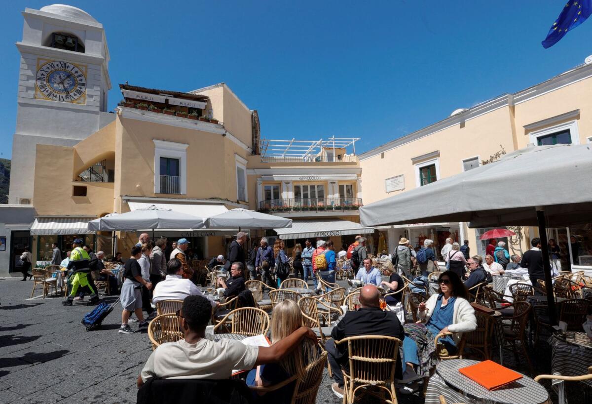 أشخاص يجلسون على الطاولات خارج المطاعم والمقاهي في جزيرة كابري بإيطاليا في 18 أبريل 2024. ر – رويترز