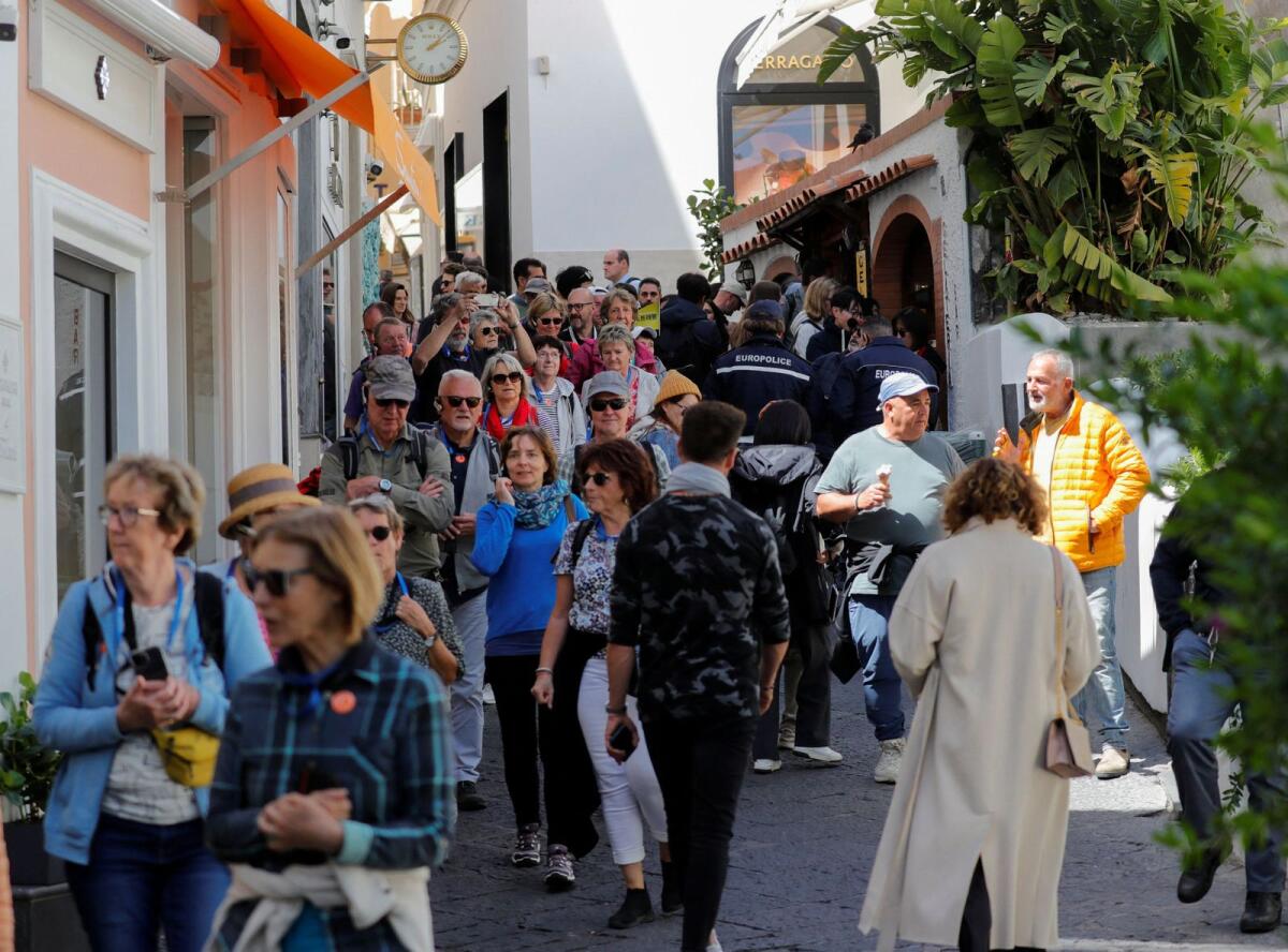 أشخاص يسيرون في الشارع بجزيرة كابري بإيطاليا في 18 أبريل 2024. – رويترز