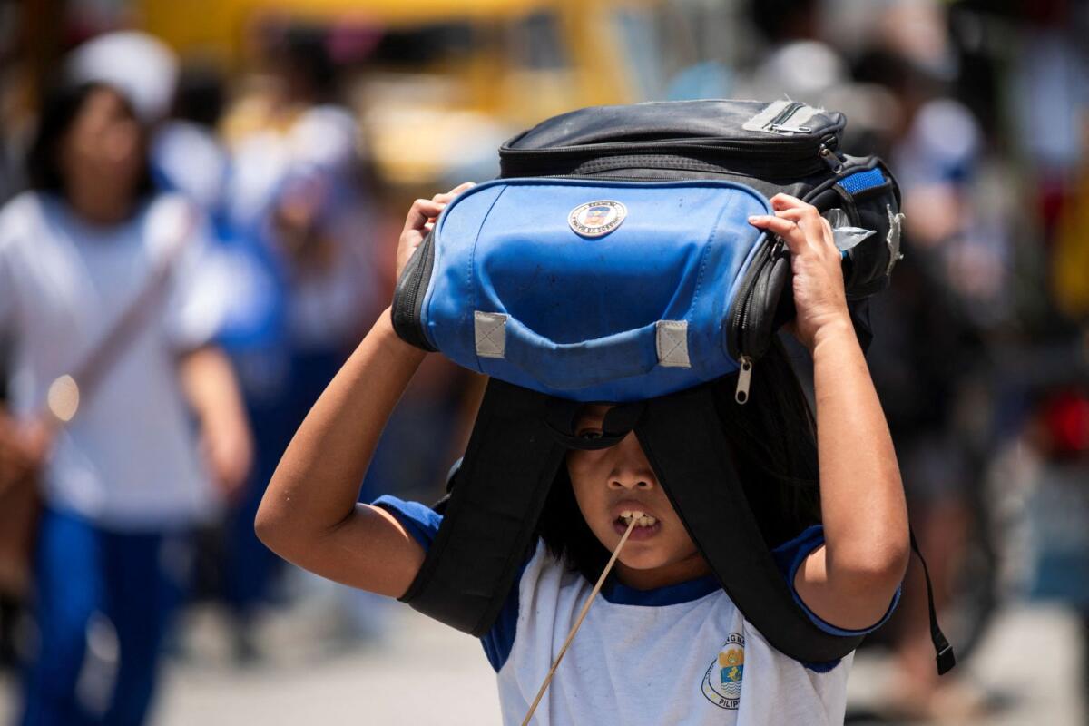 بائعة تبيع ماء جوز الهند بينما تمسح إحدى العميلات (الخلفية C) وجهها أثناء موجة الحر في مانيلا يوم الاثنين.  – وكالة فرانس برس