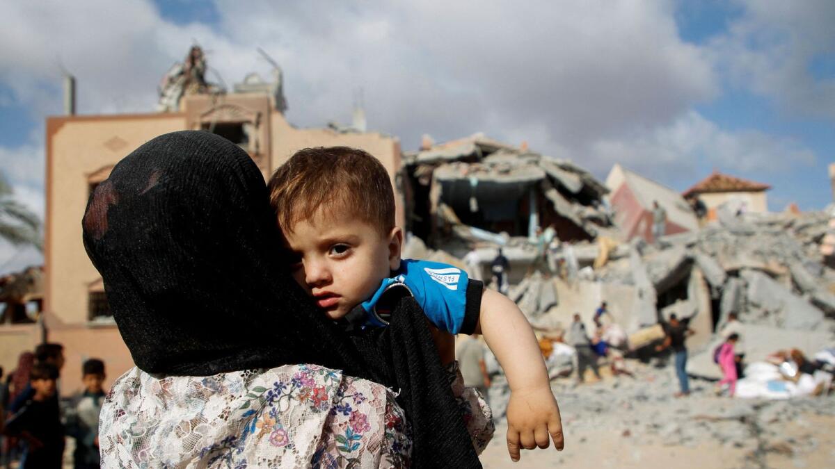 طفل فلسطيني ينظر إلى موقع الغارة الإسرائيلية على منزل في رفح.  – رويترز