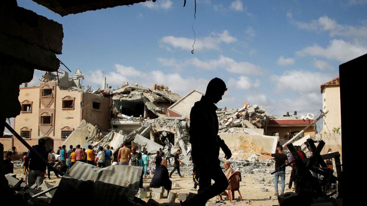 فلسطينيون يتفقدون موقع الغارة الإسرائيلية على منزل في رفح.  – رويترز