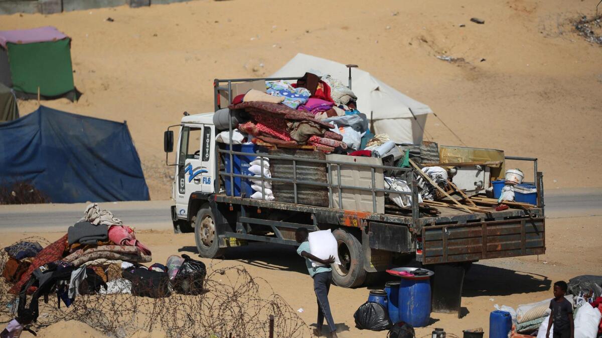 نازحون فلسطينيون يجمعون أمتعتهم على ظهر شاحنة أثناء فرارهم إلى منطقة أكثر أمانًا في رفح.  – الصورة: وكالة فرانس برس